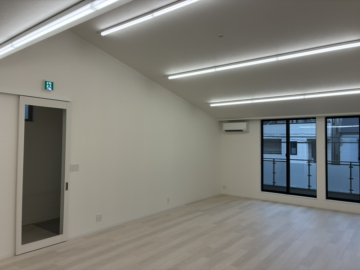 株式会社サンケイ住宅サービス様の新事務所の室内。勾配天井と大きな窓のある明るい事務所スペース